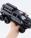 Hand holding 1/24 Diecast Pickup Truck Toy With Light And Sound, Pull Back Action Metal Truck For Kids And Collectors, Black Mammoth Model.