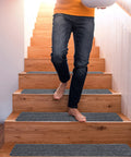 Person walking down wooden stairs with 15 Piece Indoor Stair Treads For Wooden Steps Non Slip Carpet Runner Mats With Gray Stripe Pattern
