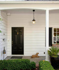 Farmhouse Outdoor Pendant Lights With Painted Black Metal And Clear Bubbled Glass Globes Hanging by White Porch