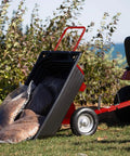Rock Solid Six Hundred Fifty Pound Poly Dump Cart For Tough Job Site Hauling with bags of debris on grass near a riding lawn mower.