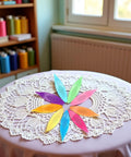 Nine Colorful Plastic Tatting Shuttles Set for Lace DIY Hand Lacemaking Craft on a lace tablecloth in a crafting room.