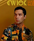 Person wearing a colorful patterned shirt, set against an orange background with abstract yellow and orange text designs.