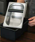 Built Like A Tank Stainless Steel Knock Box With Removable Interior Grounds Bin, shiny silver bin on black base, perfect for espresso setups.