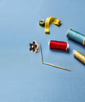 Total Fashion Hack With These Pocket Ready Black Flower Button Covers And Alloy Brooch Pins For Dresses No Sew Snap Fasteners on blue fabric with sewing supplies.
