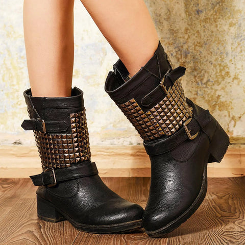 Black leather mid-calf boots, side view, with bronze pyramid studs on the shaft and buckled straps