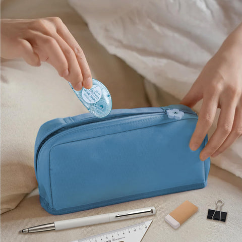 Person placing Double Sided Scrapbooking Tape Runner 4 Pack, 26 Feet By 0.31 Inch into blue pouch beside stationery.