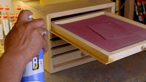 Person using 6-16-TDL Advanced Dry Lube With Teflon 9.3 oz on wooden drawer rails for smooth operation