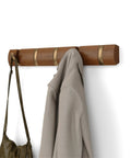 Flip Wall Mounted Coat Rack With Retractable Hooks in Light Walnut and Gold, holding a coat and bag, modern hallway organizer.