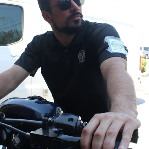 Premium Solid Durable Armband Badge Holder With Hella Secure Stretchy Strap And Easy Hook Loop Fastener For Work Credentials Cards And Passes One Size Fits worn on a man's arm while riding a motorcycle.