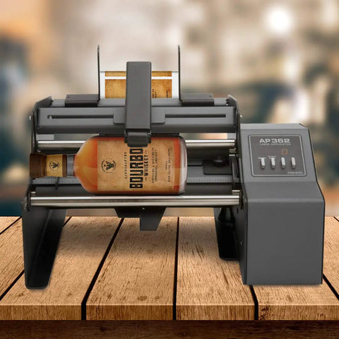 Hustle Ready Semi Automatic Label Applicator For Cylindrical Bottles Cans Jars And Tubes With No Sweat Setup and Smooth Operation Up to 1200 Per Hour For Production Lines, featuring a whiskey bottle.