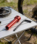 Multipurpose steel coupling sleeve with hex socket end; red metal body shown with an L-shaped Allen wrench on a portable table.