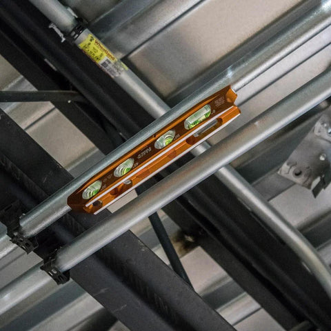 8 Inch Billet Magnetic Torpedo Level With V Groove For Precise 0 30 45 90 Degree Readings Tapered Nose High Visibility Orange Body And Secure Magnet Track For Hands Free Alignment On Metal Surfaces installed on metal pipes.