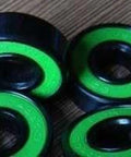 8-Pack Skateboard Black Bearings - Bronze Cage & green Seals 8x22x7mm showing black bearings with green seals.