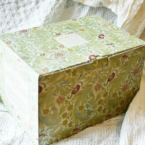 Floral patterned gift box on textured fabric background.