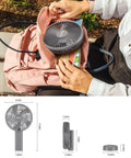 Person placing Ultra Quiet 6 Inch Handheld Personal Fan With 6 Speeds Rechargeable Battery into a pink backpack on a bench.