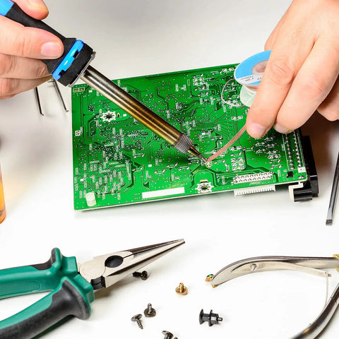 Hands using Six Piece Solder Wick Braided No Clean Desoldering Wicks Set on PCB with tools in electronics repair setup.