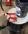Person using Lincoln 1335 Lever Action Fluid Transfer Pump on 55-gallon drum, with removable hose and brass rings, visible in workspace.