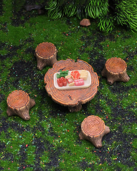 Top view of Totally Adorable Miniature Fairy Garden Furniture Set With Resin Table And Four Stump Seats Whimsical Outdoor Indoor Landscape Decor Kit For Micro Gardens on grassy surface.