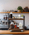 Dope Vintage Two Tier Mini Wood Coffee Bar Cart With Smooth Rolling Wheels And Spacious Dual Shelves For Any Cozy Hangout Or Quick Serve Beverage Station on wooden counter.