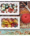 20 Pcs Kraft Paper Gift Boxes With Window showing candies, placed with scissors and yarn on a wooden surface.