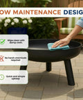 Person cleaning 27.5 Inch Outdoor Wood Burning Fire Pit With Handles And Cover Black Lightweight 17.5 Lb Portable Fire Pit