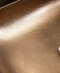 Close-up of gold plated rectangular bathroom vessel sink surface with a smooth finish and drain opening.
