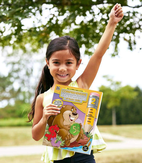 Child outdoors holding All In One Second Grade Comprehensive Skills Workbook For Reading Math Language Arts Spelling Grammar And Writing