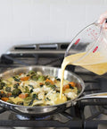 Angled 2 Cup Measuring Cup With Easy Read From Above Measurements pouring mixture into skillet on stove