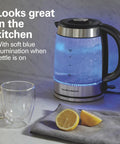 Electric Tea Kettle With 1500 Watts For Fast Boil 1.8 Liter Water Boiler Cordless Serving Auto Shutoff Boil Dry Protection Easy View Glass Lift Out Lid with blue LED illumination next to a glass and lemon slices on a kitchen counter.