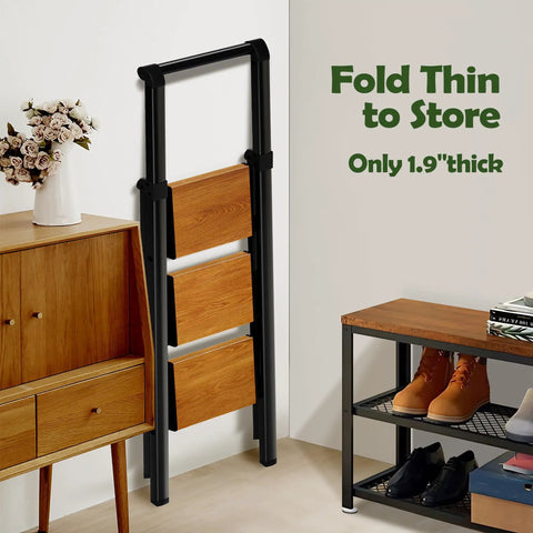 Three Step Foldable Aluminum Ladder With Black Woodgrain Finish, Lightweight Space Saving Step Stool For Home Kitchen And Garage Opens To 44.8 In High 18.9 In Wide 25.9 In Deep Top Step At 26.7 In 9 In Between Steps folded thin against wall