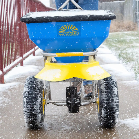 Person using Spyker Winter Weather Deicing Kit With Ergo Pro 50 Pound Spreader on snowy sidewalk