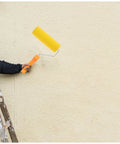 Textured Sponge Paint Roller For Wall Painting With Ergonomic Handle held by a person on a ladder against a light wall.