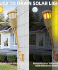 Upgraded Flickering Flame Solar Powered Torches to Light Up Outdoor Gardens and Patios Waterproof Decorative Lighting with Realistic Flame Patterns Handmade Bamboo Weave Look Energy Saving Weatherproof 2 Pack installed beside house wall