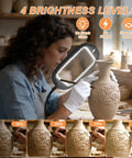 Artist using Upgraded 30X And 10X Floor Magnifying Glass With Light And Stand to examine pottery with brightness levels.