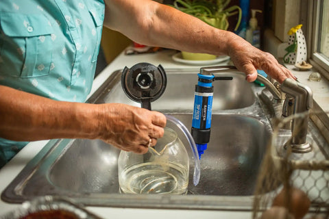 Person installing Tap Water Filtration System With 0.1 Micron Inline Filter, Fits Faucets And Hose Bibs in kitchen sink
