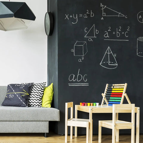 Room with black wall used as chalkboard, showcasing Chalkboard Paint For Walls In Black 1 Quart with math drawings, sofa, and table.