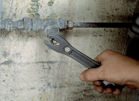 Hand using Alligator Adjustable Wrench, 8 Inch, Slim Head With Tapered Jaws For Easy Reach And Extra Turning Power on a pipe fitting