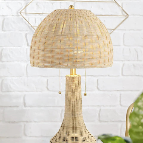 Bohemian Rustic 22 Inch LED Table Lamp with Natural Rattan Shade and Brass Gold Finish on white brick background