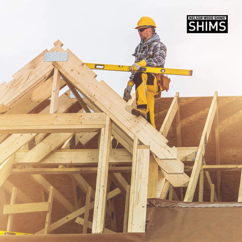 Construction worker using level on wooden framework, showcasing 8 Inch Wood Shims For Leveling Pro Pack 120 Count Wedges For Toilets Tables