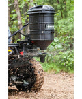 ATV Spreader With Manual Feed Gate For Seed Or Fertilizer, 100 Pound Hopper, Heavy Duty 12 Volt Motor in use on a forest trail