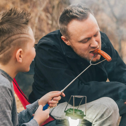 Father and son using 45 Inch Extra Long Marshmallow Roasting Sticks Kit For Campfire Smores, 4 Pack Telescoping Skewers.