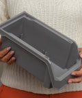 Medium Plastic Storage Bin in gray, held by person in a sweater, with open front design for easy access.