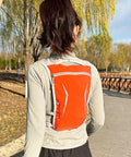 Person wearing orange All Day Hydration On The Go Lightweight Running Hydration Backpack With Built In Reservoir outdoors