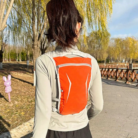 Person wearing orange All Day Hydration On The Go Lightweight Running Hydration Backpack With Built In Reservoir outdoors