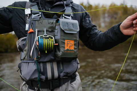 Angler wearing Stormshadow Fly Fishing Chest Pack with Waterproof Pocket, Velcro Fly Patch, and Tool Attachment Points by a river.