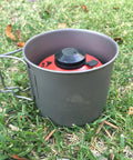 Ultralight Titanium 550ml Pot With Lid For Backpacking And Camping on grass with stove gear visible inside