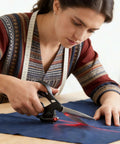 Professional laser-guided fabric scissors with ergonomic handle cutting blue fabric; red laser line visible