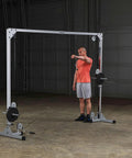 Man using Beefy Heavy Duty Cable Crossover Machine For Home Gym Functional Trainer with dual pulleys in a gym setting.