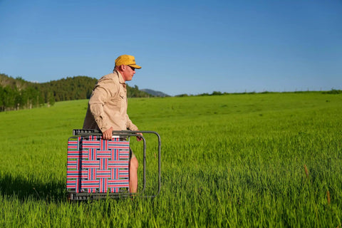 Man carrying Retro Webbed Camping Chair With Foldable Steel Frame Lightweight 8 Lb in field, red white blue stripes visible