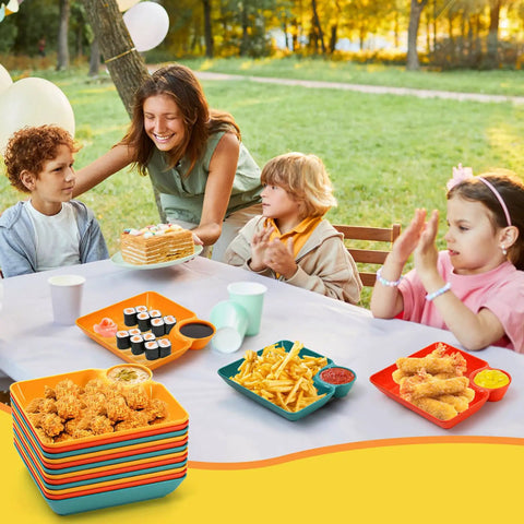 Colorful 12 Piece Chip and Dip Serving Platter Set BPA Free Plastic Snack Trays at outdoor party with sushi and chicken.